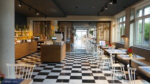 A cafe with a checkered floor, wooden counters, and seating areas with tables and chairs. - Flowers Hotel Essen (Essen)