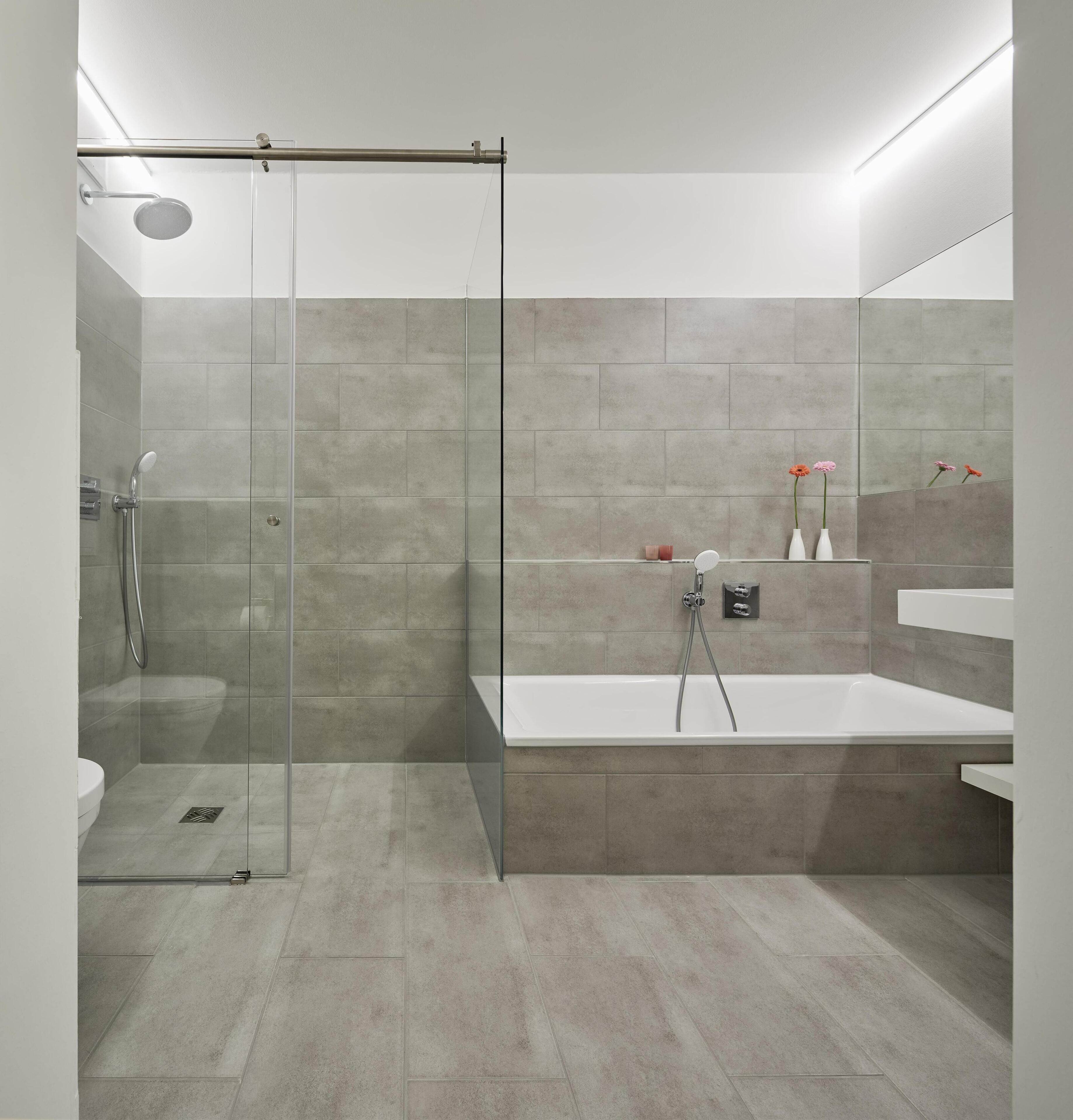 A modern bathroom with a glass shower enclosure, a freestanding bathtub, and a large mirror.