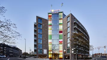Un hotel moderno con fachada colorida, varios pisos y una entrada destacada.