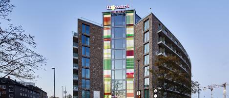 A modern hotel with a colorful facade, multiple floors, and a prominent entrance.