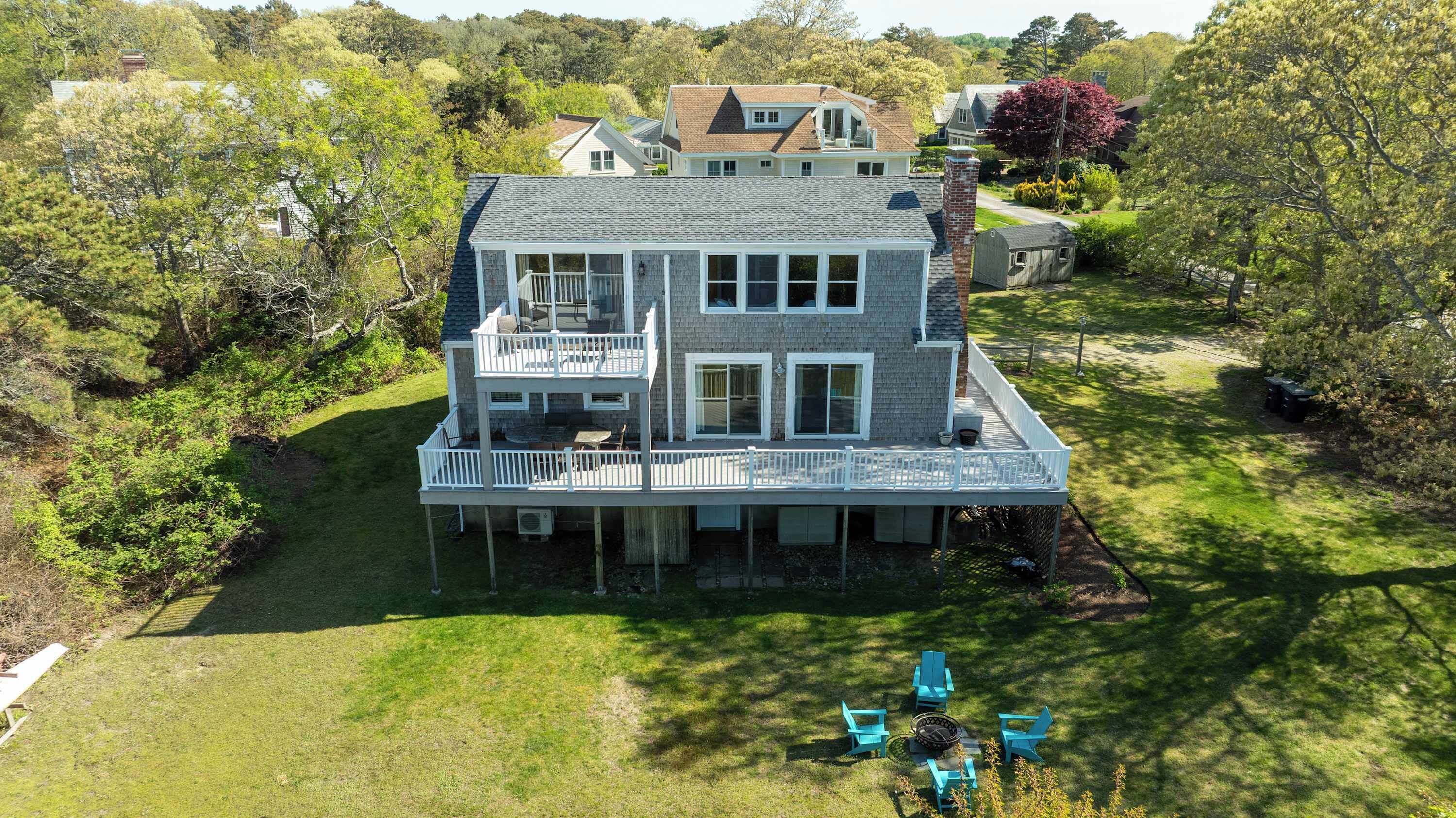 A two-story house with a balcony, surrounded by a well-maintained lawn and trees.
