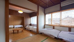 Ein traditioneller japanischer Raum mit Tatami-Boden, niedriger Holzbalkendecke und verschiebbaren Shoji-Schirmwänden.