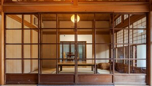 Ein traditioneller japanischer Raum mit Tatami-Böden, Schiebetüren und Blick in einen Essbereich.