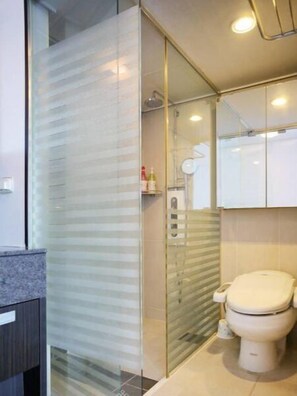 Bathroom features a glass shower enclosure, handheld showerhead, and a standard toilet.