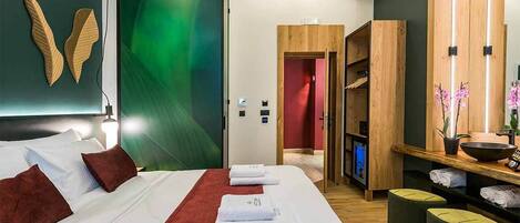 Una habitación de hotel moderna con una cama grande, una pared de acento roja, muebles de madera y una obra de arte abstracta verde en la pared.