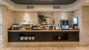 A buffet setup with a variety of food items, a coffee machine, and a fruit display. - Artion City Boutique Hotel (Heraklion)