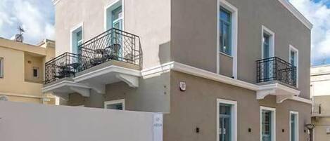 Un edificio de dos pisos con fachada color beige, balcones y una entrada con portón.