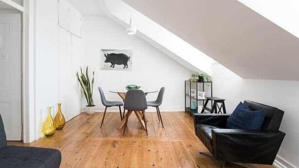Een modern loft appartement met een eethoek, een zwarte leren bank en een wanddecoratie van een zwart varken.
