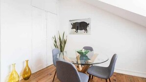 Een eetgedeelte met een glazen tafel, vier grijze stoelen en twee gele vazen op de vloer.