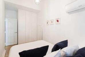 A bedroom with a bed, a wardrobe, and an air conditioning unit. - Excellent Location A/C and views in Principe Real (Lisboa)