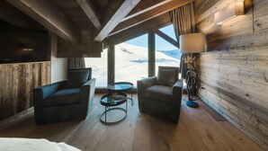Um quarto acolhedor com paredes de madeira, uma janela grande e vista para uma paisagem nevada.