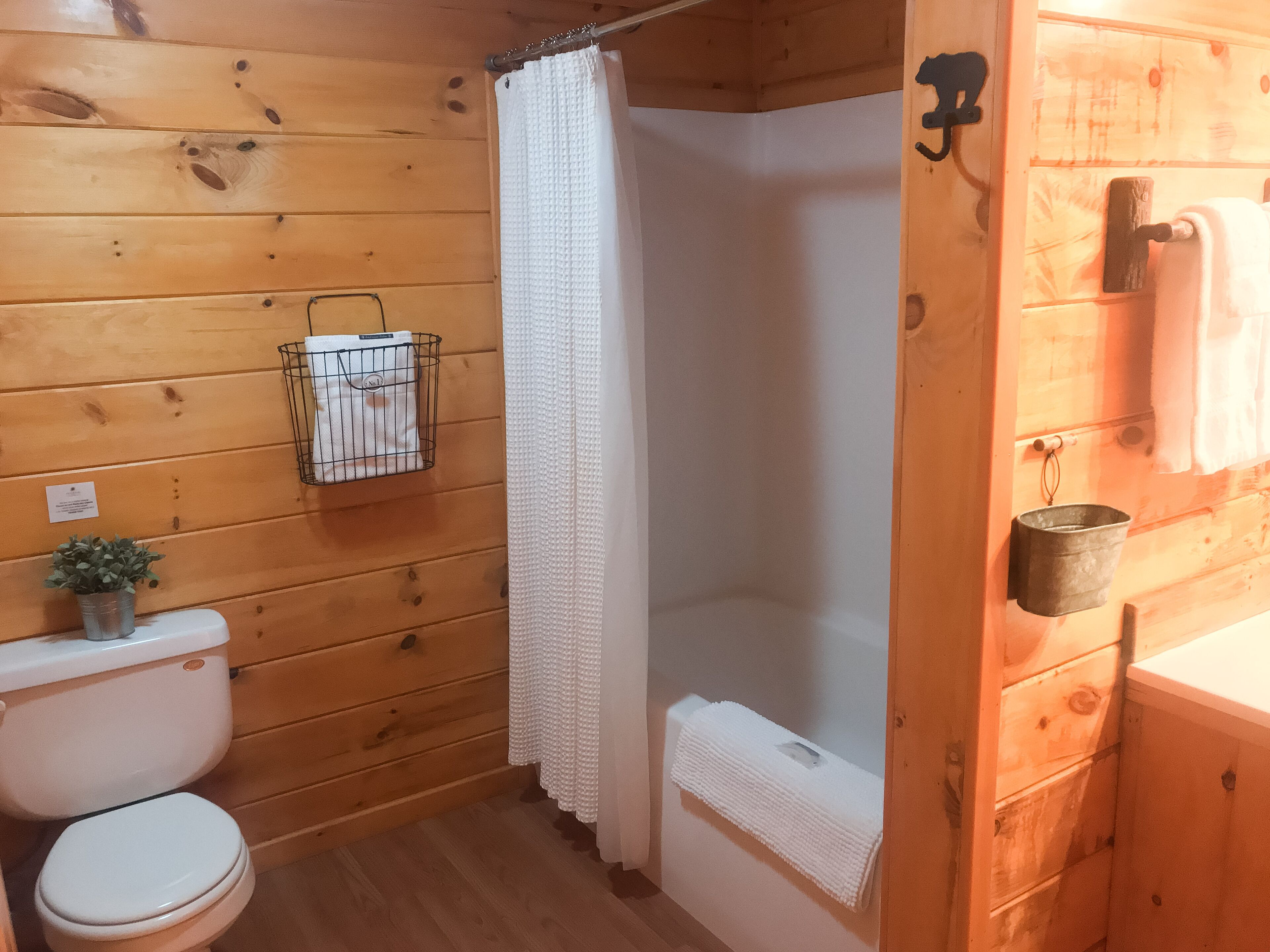 Une salle de bain rustique, aménagée dans une cabane en bois, avec des toilettes, une douche et un porte-serviettes.