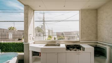 A modern bathroom with a large window, a built-in sink, and a bathtub.