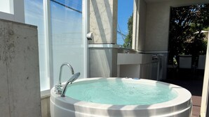 A large outdoor hot tub with a modern design, surrounded by a concrete deck and a glass enclosure. - Casablanca Pool House (Kamakura)