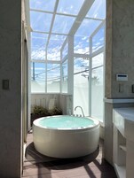 Casa de banho com uma banheira grande, uma janela e vista para o céu.