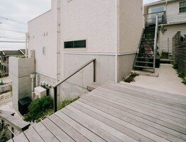 A modern building with a concrete exterior, a wooden staircase, and a metal handrail.