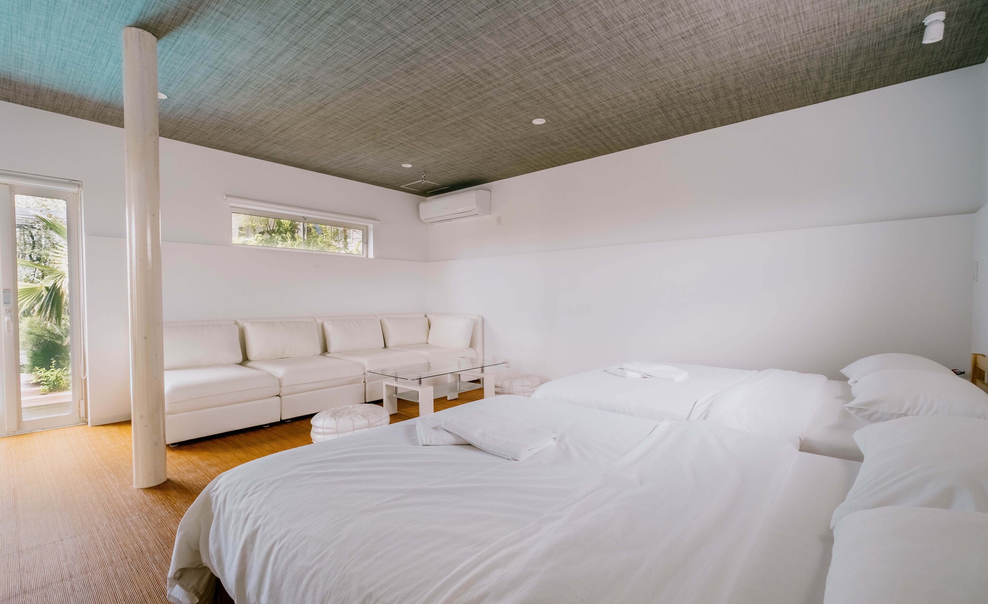 Une chambre moderne avec un grand lit, un canapé blanc et une petite table.