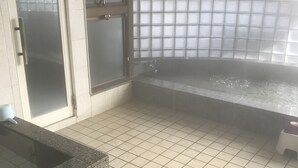 A bathroom with a tiled floor, a granite countertop, a glass shower enclosure, and a frosted glass window. - Business hotel route9 (Matsue)