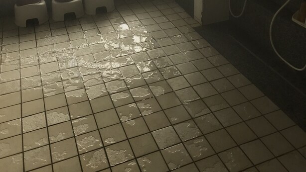 A bathroom with a tiled floor, a window with a grid pattern, and a handwashing station. - Business hotel route9 (Matsue)