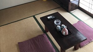 A traditional Japanese-style room with tatami flooring, a low table with a tray of items, a television, and a sliding door with a view. - Business hotel route9 (Matsue)