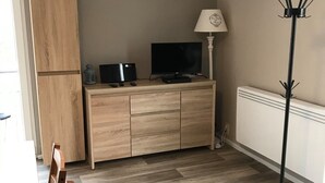 Une cuisine moderne avec des meubles en bois, un téléviseur et un lampadaire.