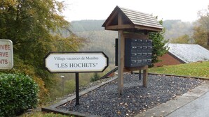 Un panneau indiquant le « Village de vacances de Membre « LES HOCHETS » », avec une structure en bois et une boîte aux lettres.