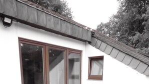 Une terrasse avec une table ronde et quatre chaises, une porte-fenêtre coulissante et une petite fenêtre.