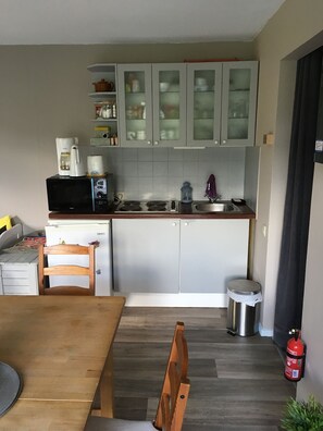 Una cocina compacta con microondas, cafetera y alacenas sobre la encimera.