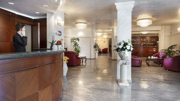 A hotel lobby with a reception desk, seating area, and bar.