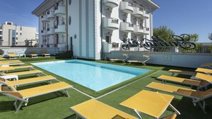 A rooftop pool area with yellow sun loungers and a large pool.