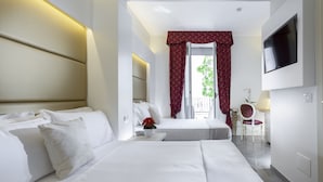 A hotel room with two beds, a TV mounted on the wall, a small table with a vase of flowers, and a chair.