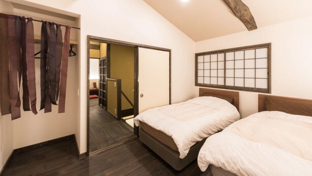 A bedroom with two beds, a wooden ceiling, a sliding door leading to a hallway, and a shoji screen on the wall. - Hotel Zipangu Tameikecho (Kyoto)