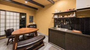 A compact kitchen with a wooden dining table, a bench, and a built-in sink. - Hotel Zipangu Tameikecho (Kyoto)