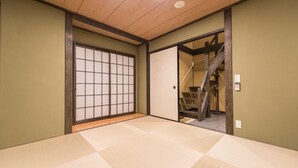 A room with tatami flooring, a shoji screen door, and a wooden staircase leading to an upper level. - Hotel Zipangu Tameikecho (Kyoto)