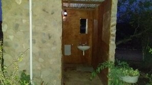 Un baño con paredes de piedra, una puerta de madera, una ventana pequeña y un lavamanos.