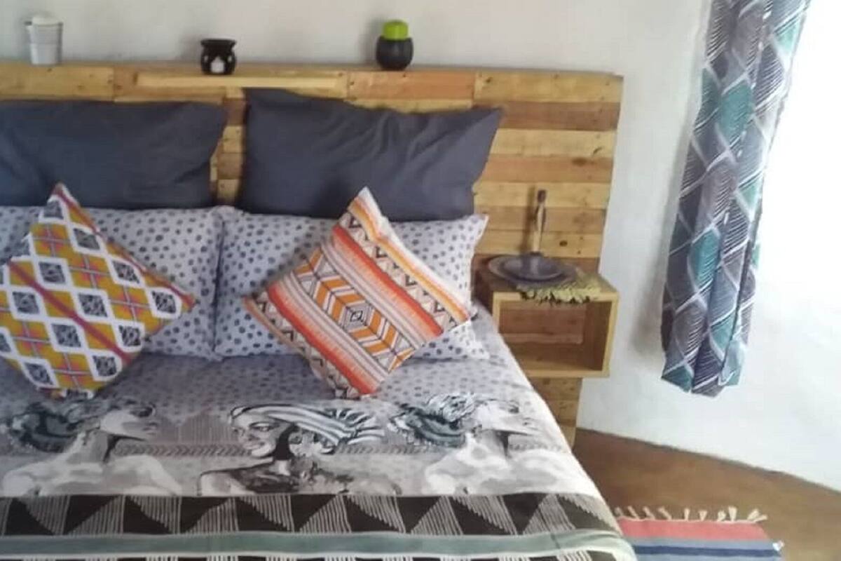 A bed with a patterned bedspread, two pillows, and a wooden headboard.