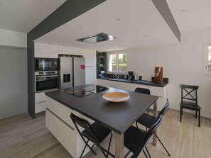 A modern kitchen with a central island, built-in appliances, and a view to the outdoors.