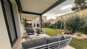 A covered patio area with a white sofa, a small table, and a chair. - Villa with 132 m2 of living space large living area large terrace and landscaped garden (Vias)