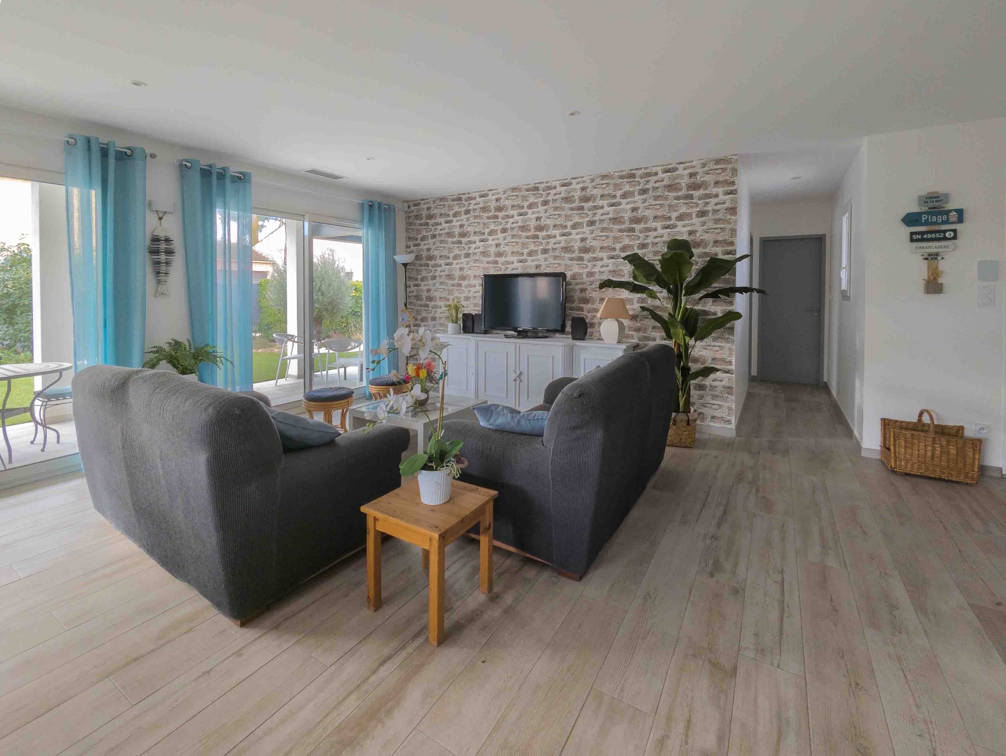 Una sala de estar con pared de piedra, televisor y vista al exterior.