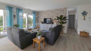 A living room with a stone wall, a television, and a view of the outdoors. - Villa with 132 m2 of living space large living area large terrace and landscaped garden (Vias)