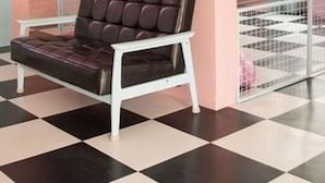 A room with a checkered floor, a brown leather sofa, and pink walls. - Fanhua (Seoul)