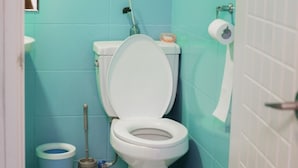 A bathroom with a toilet, a bidet, a toilet brush, a roll of toilet paper, and a small trash bin. - Fanhua (Seoul)