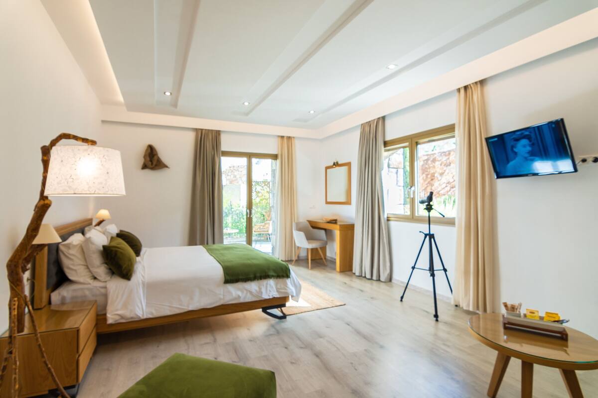 Une chambre à coucher moderne, équipée d’un lit, d’une table de chevet, d’une lampe, d’un bureau, d’une chaise et d’un téléviseur fixé au mur.