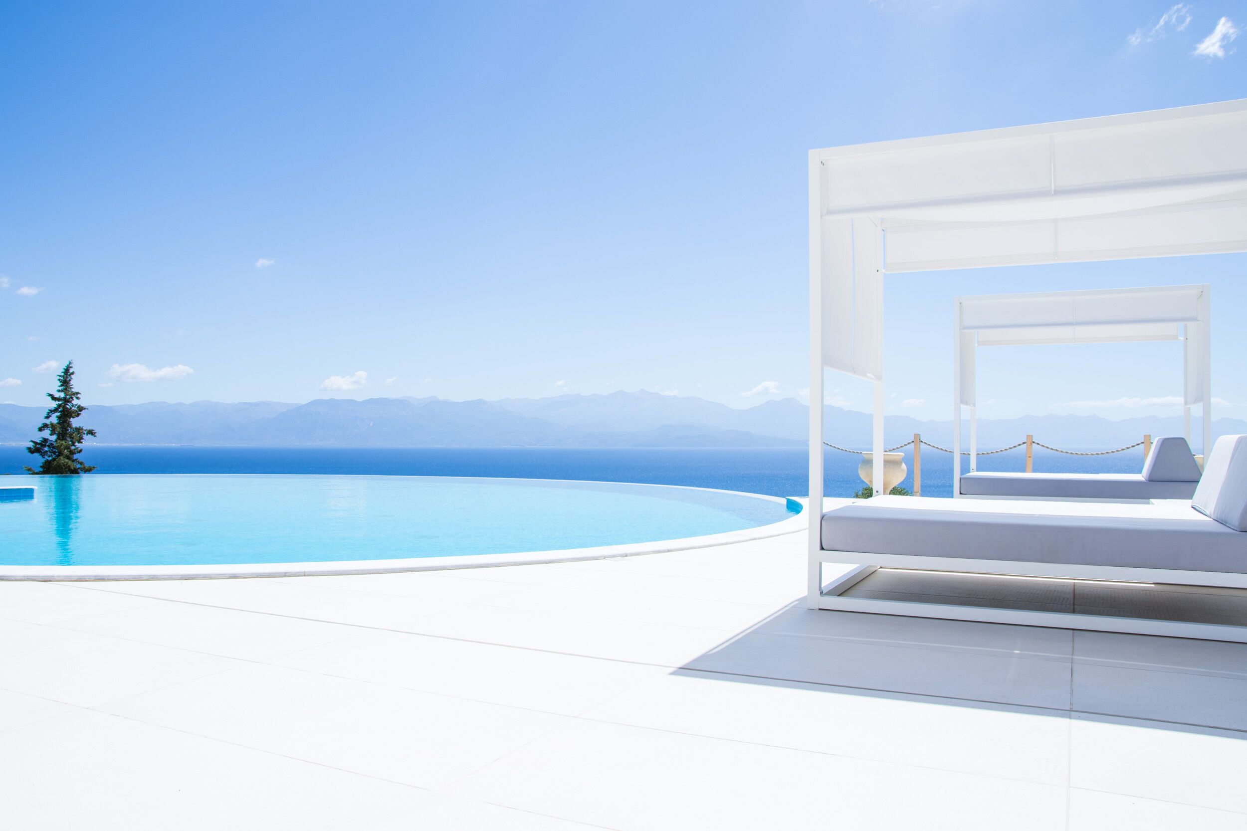 A modern infinity pool with a clear view of the sea and mountains.