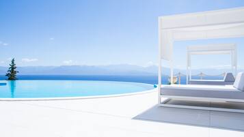 A modern infinity pool with a clear view of the sea and mountains.