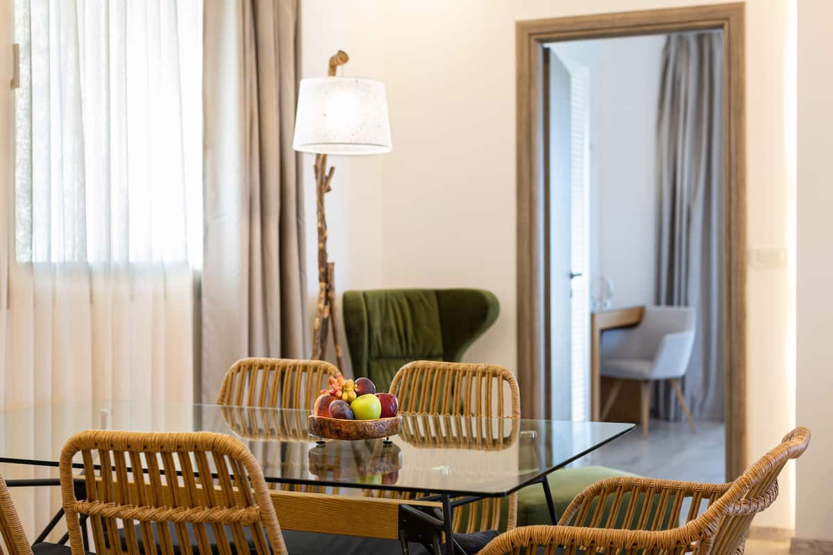 Un coin repas avec des chaises en osier, une table en verre et un panier de fruits.