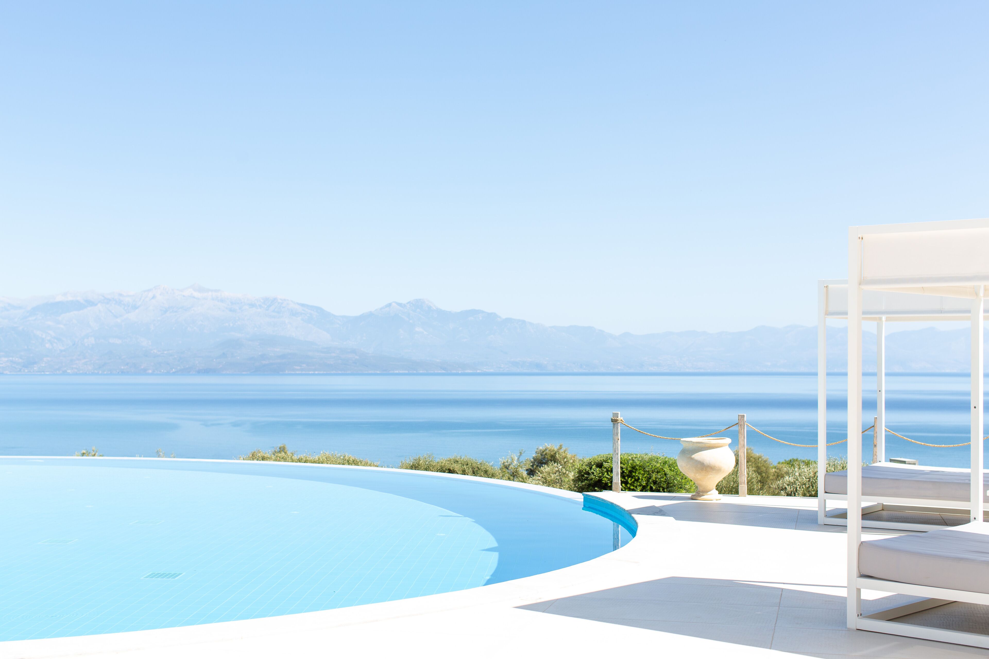 A pool with a view of the sea and mountains.