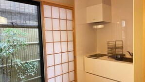 A kitchen with a bamboo screen door, a sink with a dish rack, and a stove. - Hotel Zipangu Murasakino (Kyoto)