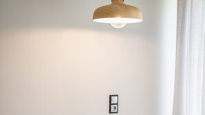 A dining area with a wooden table, two white chairs, and a pendant light. - Central Cozy Studio (Chania)