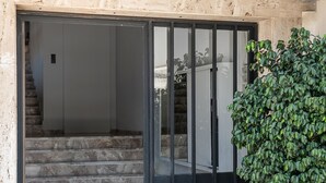 A building entrance with a glass door, a staircase leading inside, and potted plants outside. - Central Cozy Studio (Chania)